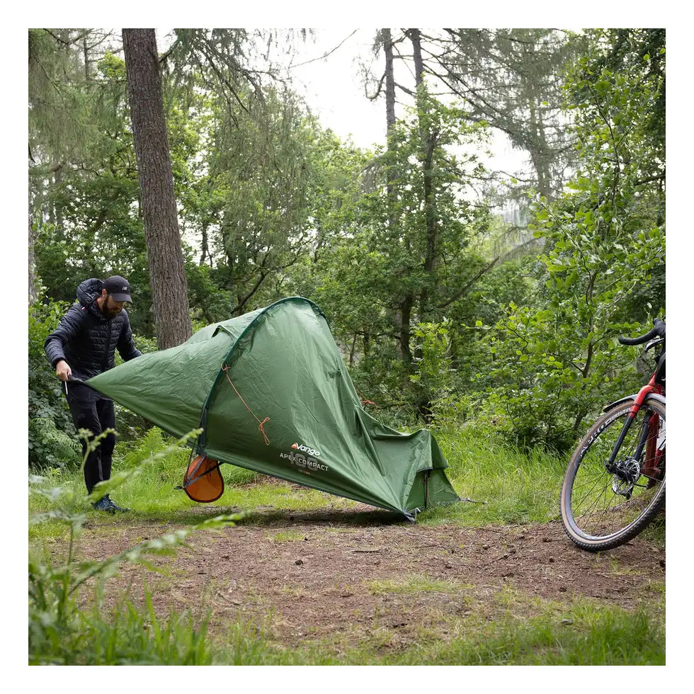 Packing down the Vango Apex Compact 100 tent beside a bike in woodland