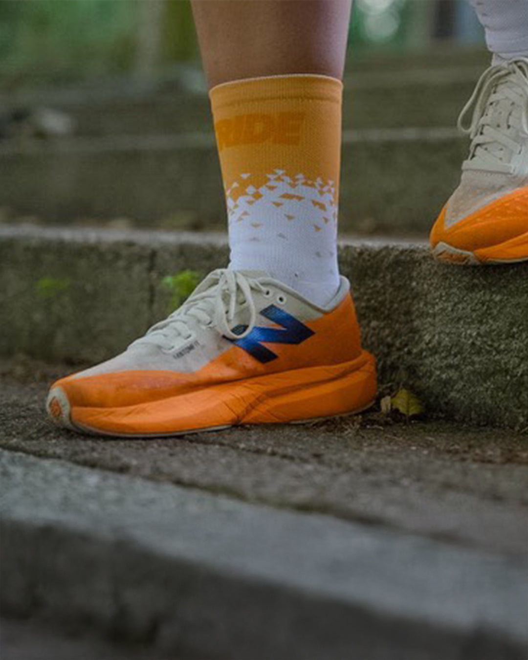 Close-up of a Stride Tropic Tempo running sock on a runner stepping up concrete steps