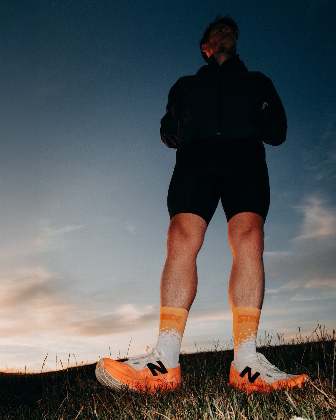 Runner standing on a grassy hilltop at dusk in Stride Tropic Tempo running socks
