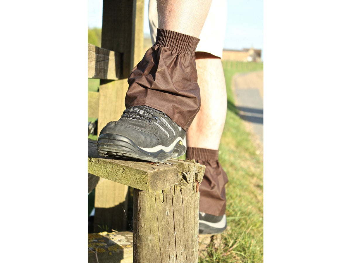 Brown oilskin hikers gaiter over a walking shoe on a wooden stile step