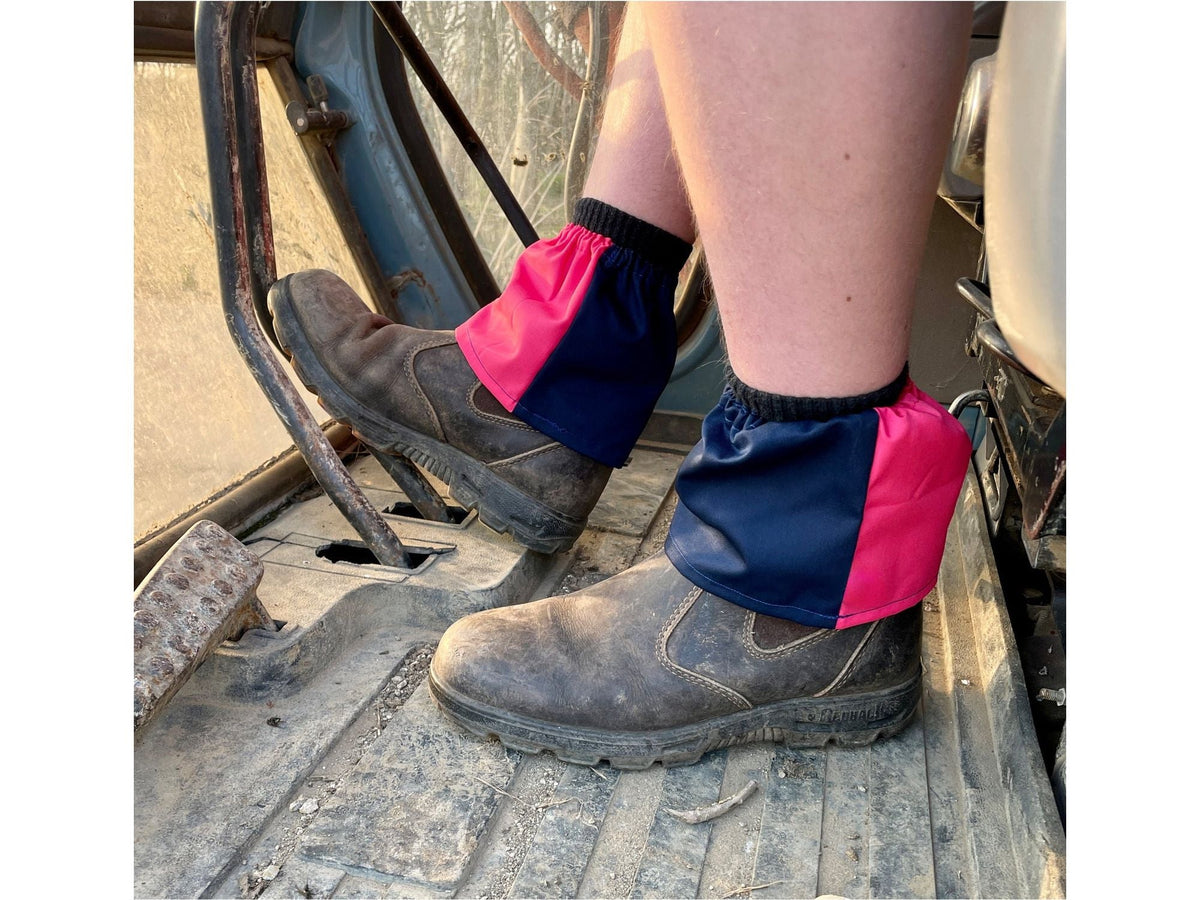 Navy and fuchsia harlequin sox savers worn over work boots in a tractor footwell