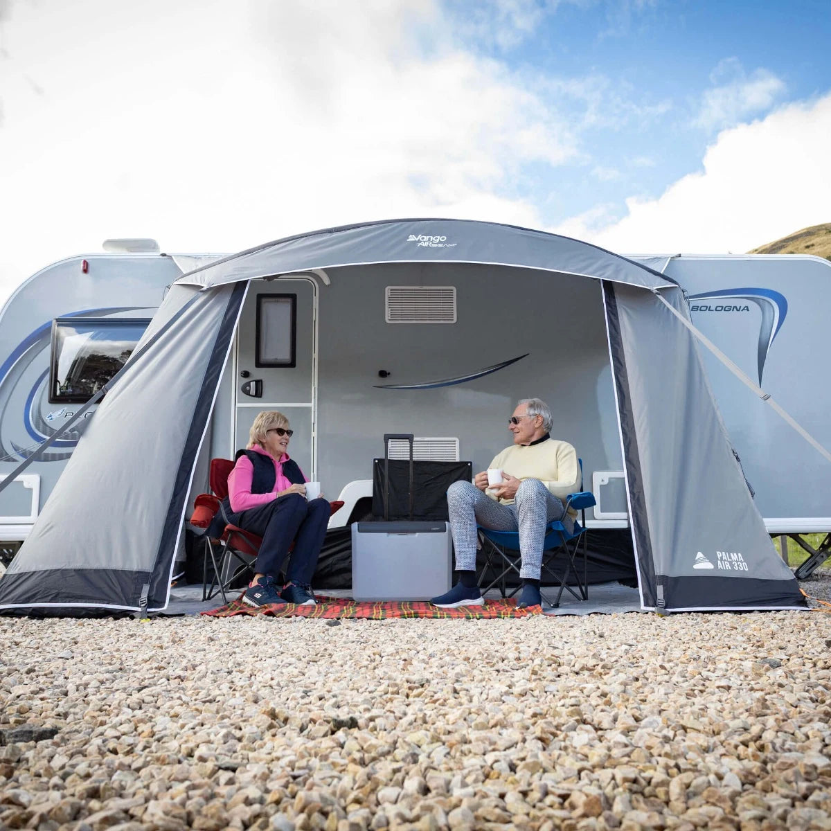 Couple relaxing in the Vango Palma Air 330 awning on a hillside campsite