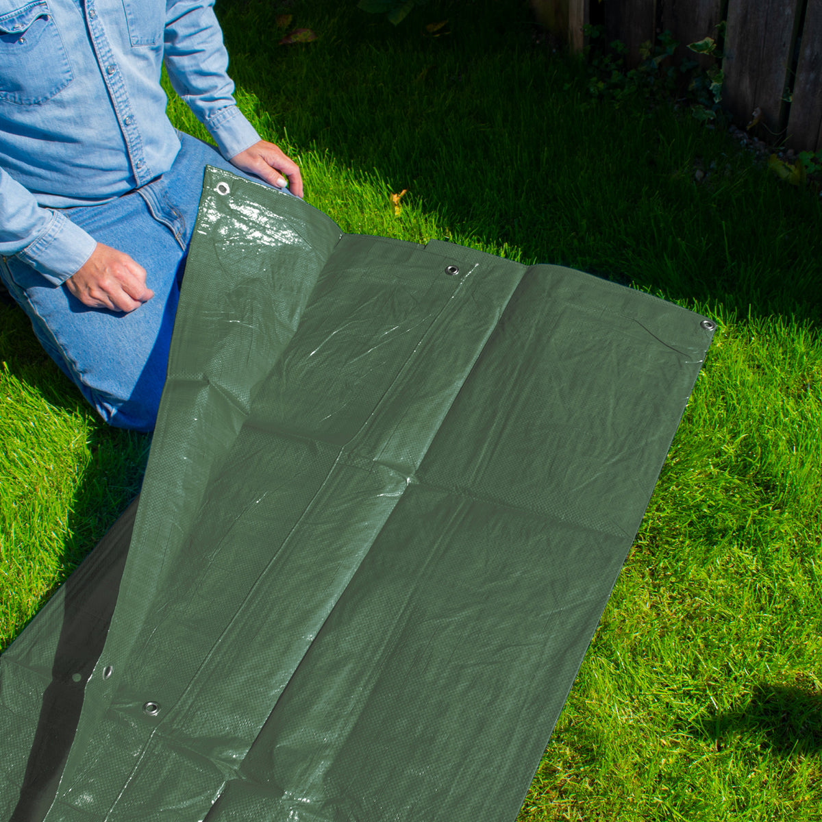 Green M-Grade Tarpaulin 5m x 8m laid out on a lawn beside a garden border