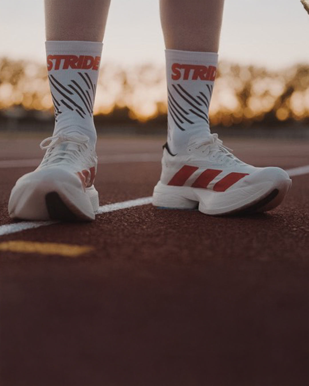 Runner standing on an athletics track at sunset in Stride Race Core running socks