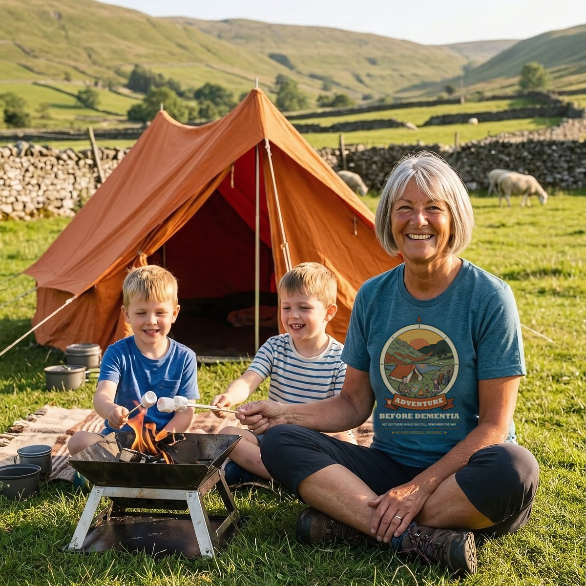 Woman in the Adventure Before Dementia Camping T-Shirt in Heather Deep Teal toasting marshmallows with two children at a Dales campsite