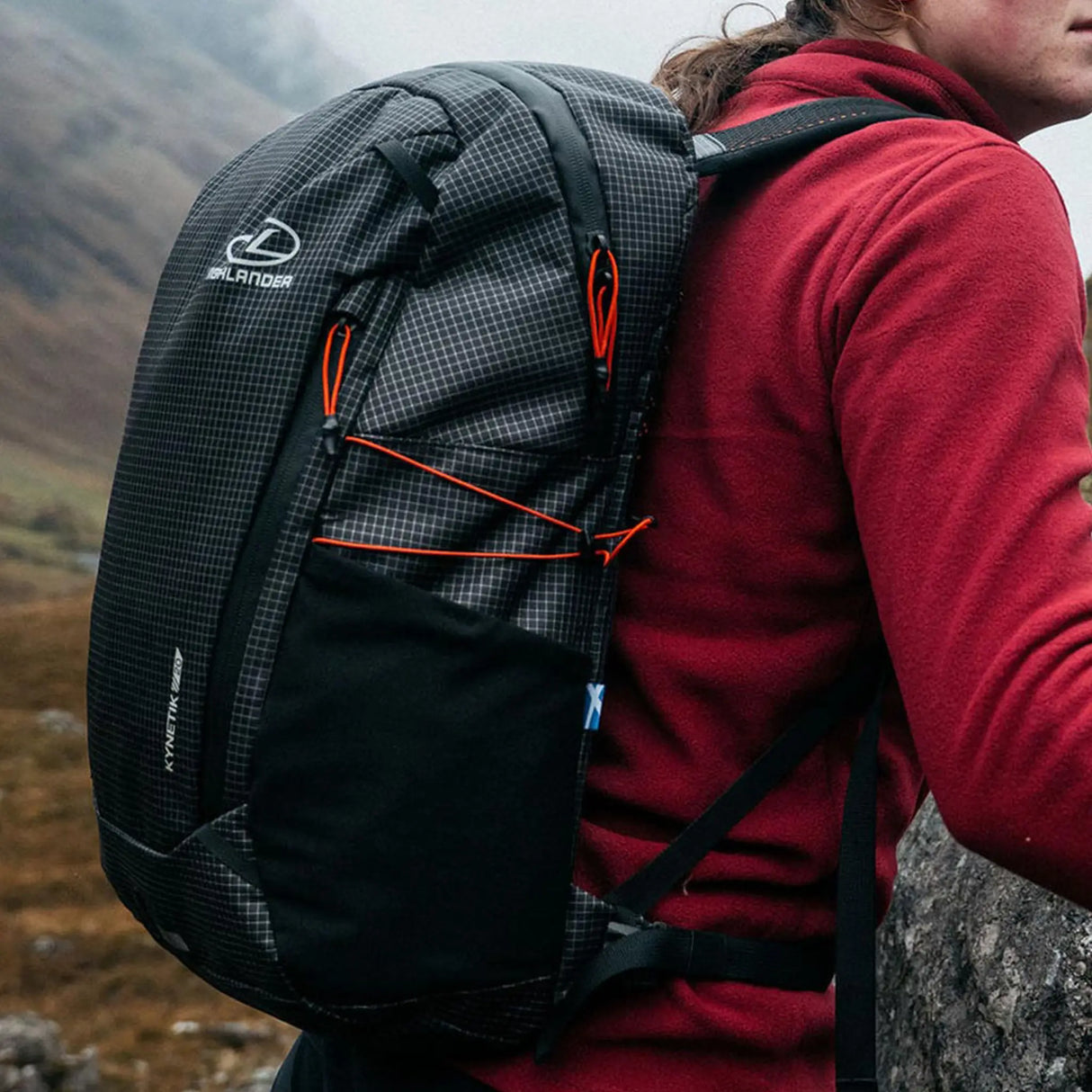 Highlander Kynetik Rucksack 20L in Black - close-up of the bungee cord and side pocket worn on the hill
