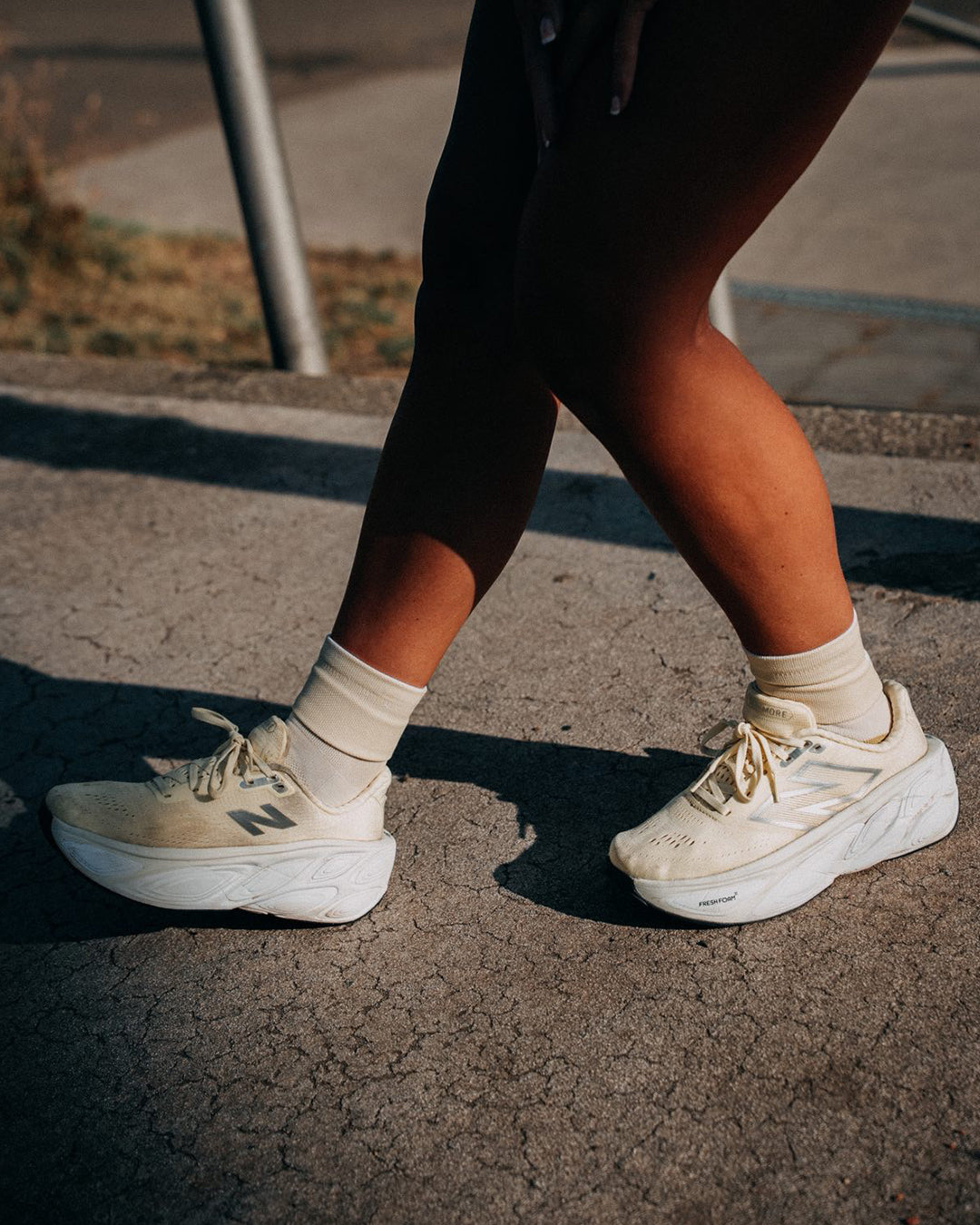 Runner walking on a sunlit tarmac path in pale cream socks and cream running shoes