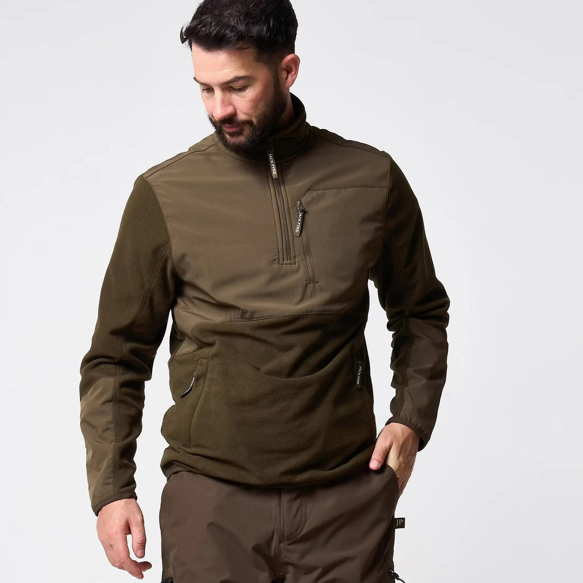Jack Pyke Rannock Fleece Pullover in dark olive worn by a model looking down, front view showing both zipped lower pockets