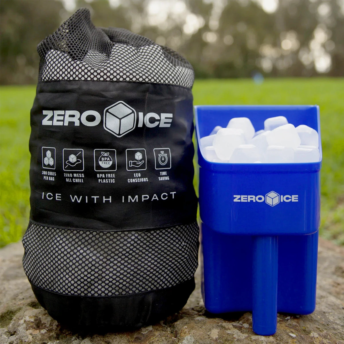 Blue Zero Ice scoop of clear cubes beside a Zero Ice mesh bag, outdoors on a rock