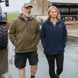 Two people wearing Sugar Loaf Shepherd Polar Fleece Hoodie in Khaki standing on a farm with a tractor and barn in the background.