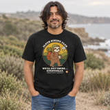 Man standing on a coastal hillside wearing the Sloth Hiking Club: Walking T-Shirt in Vintage Black