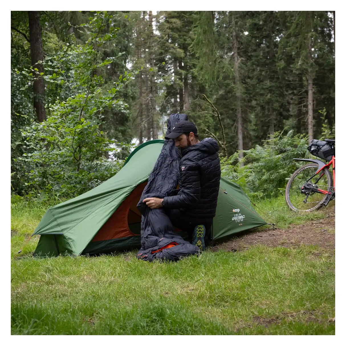 Camper sitting in the porch of the Vango Apex Compact 100 tent in woodland