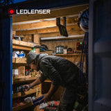 Tradesman at the shelves of a site container, lit by a Ledlenser area light hanging from its handle