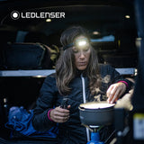 Woman cooking in the back of a van, lit by a Ledlenser head torch