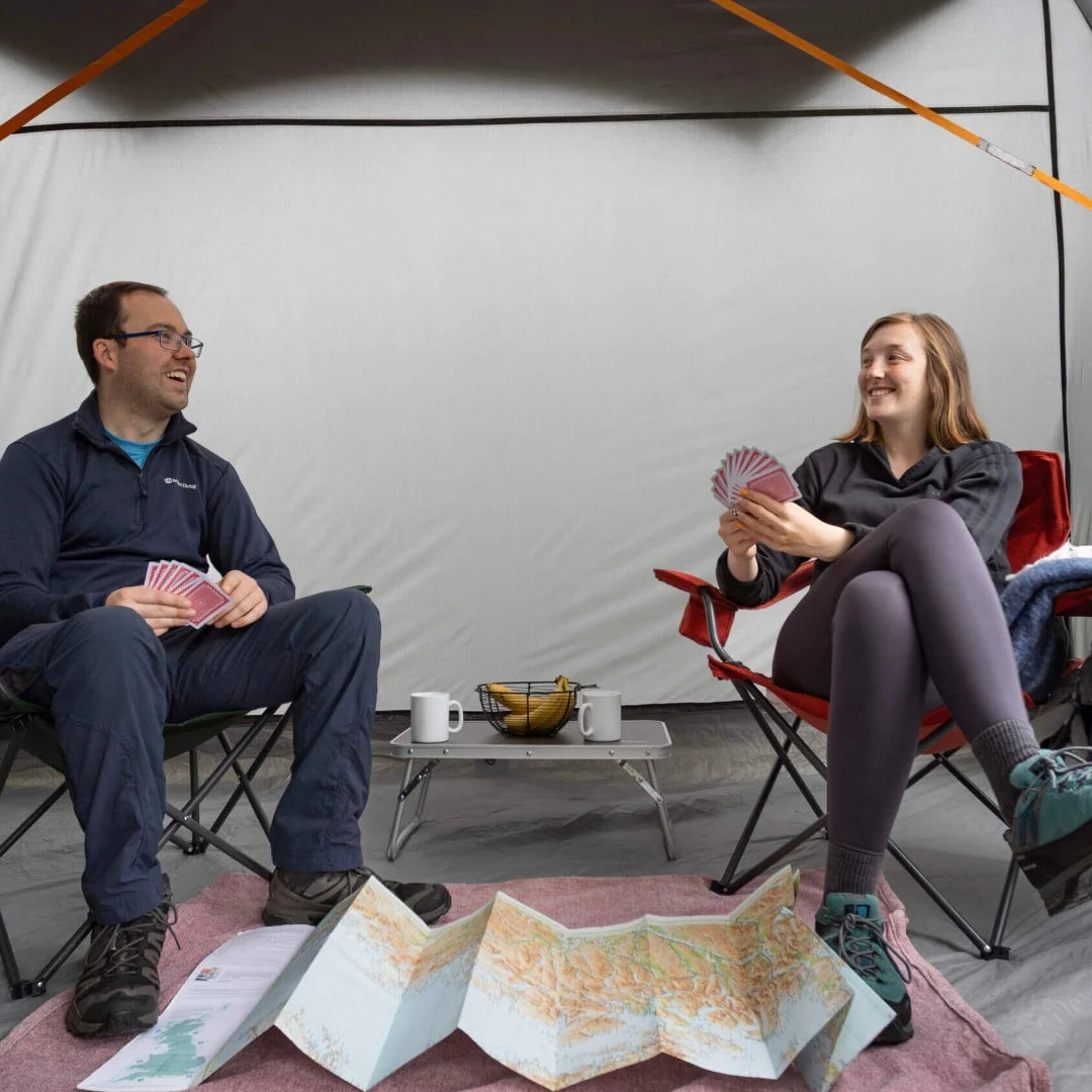 Two campers playing cards inside the Vango Cove III drive away awning