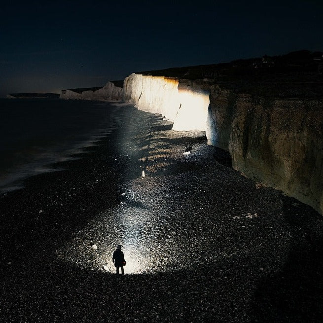 Person on a beach at night lighting up chalk cliffs with the Ledlenser XP30R