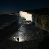 Person on a beach at night lighting up chalk cliffs with the Ledlenser XP30R