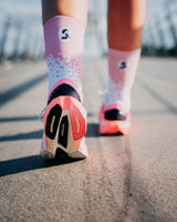 Rear view of a runner on a bridge in Stride Flash Pink running socks, pink cuff with S logo