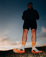 Runner standing on a grassy hilltop at dusk in Stride Tropic Tempo running socks