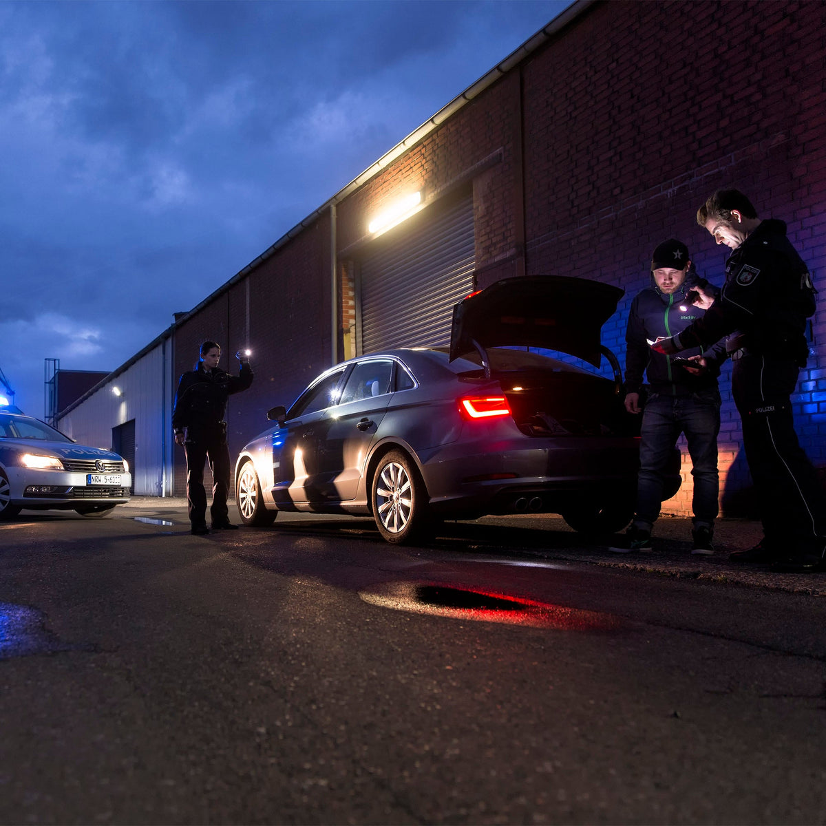 Officers checking a car boot at night by torchlight