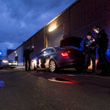 Officers checking a car boot at night by torchlight