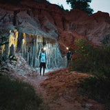 Two hikers lighting eroded rock formations at dusk with Ledlenser head torches
