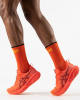 Runner's lower legs in Stride Heat Surge half crew running socks with red-orange running shoes
