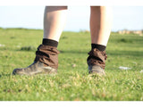 Pair of brown oilskin sox savers worn over dealer boots on a grass field
