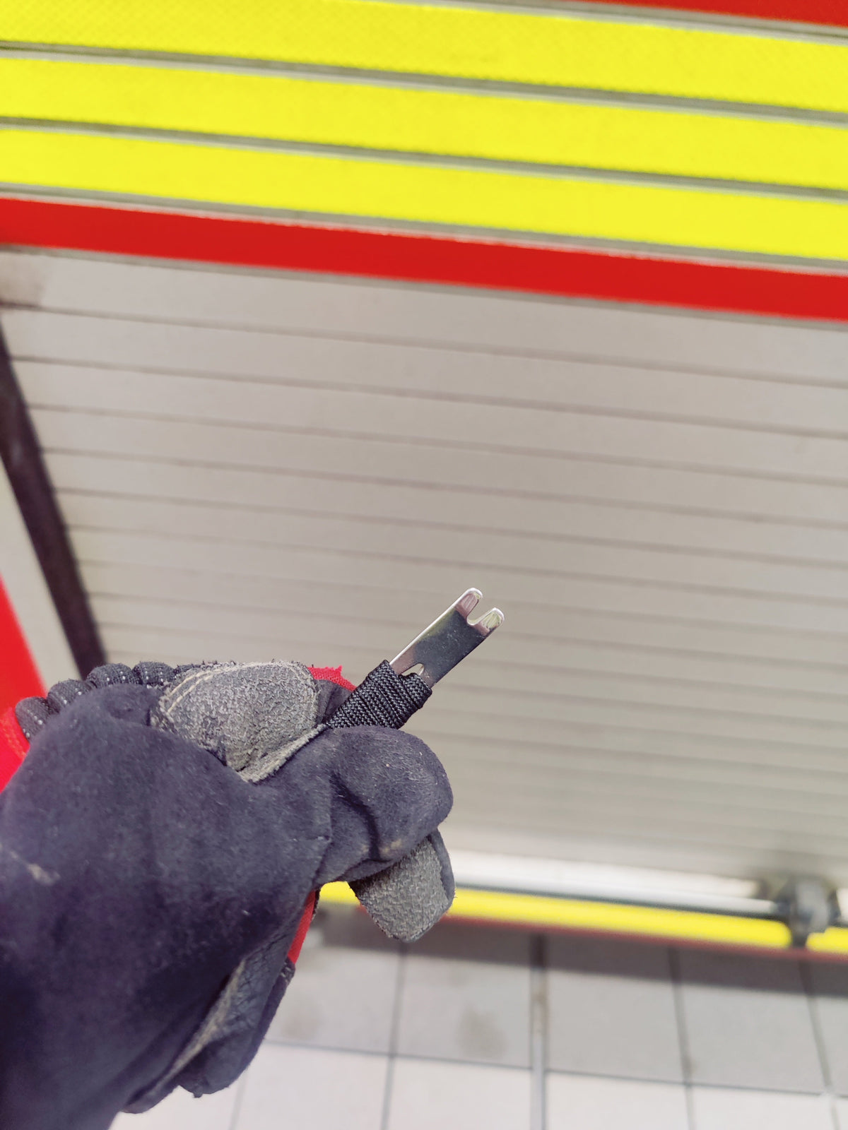 Black Mini Pry Bar gripped in a firefighter's glove, notched tip showing
