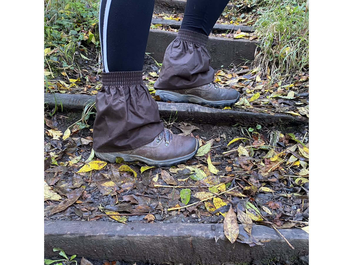 Brown oilskin hikers gaiters worn over walking boots on muddy woodland steps