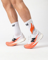 Runner's lower legs in Stride Ember Ignite half crew running socks with white and coral running shoes