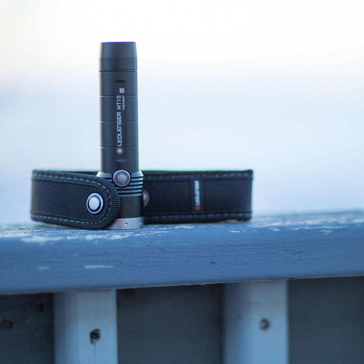 Ledlenser MT10 torch standing beside a belt pouch on a frosty rail