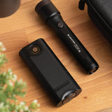 Ledlenser FLEX10 power bank lying on a wooden table beside a Ledlenser P7R Core torch