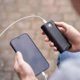 Ledlenser FLEX10 held in one hand charging a smartphone by cable