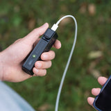 Ledlenser FLEX5 held outdoors with a cable plugged in to charge a phone
