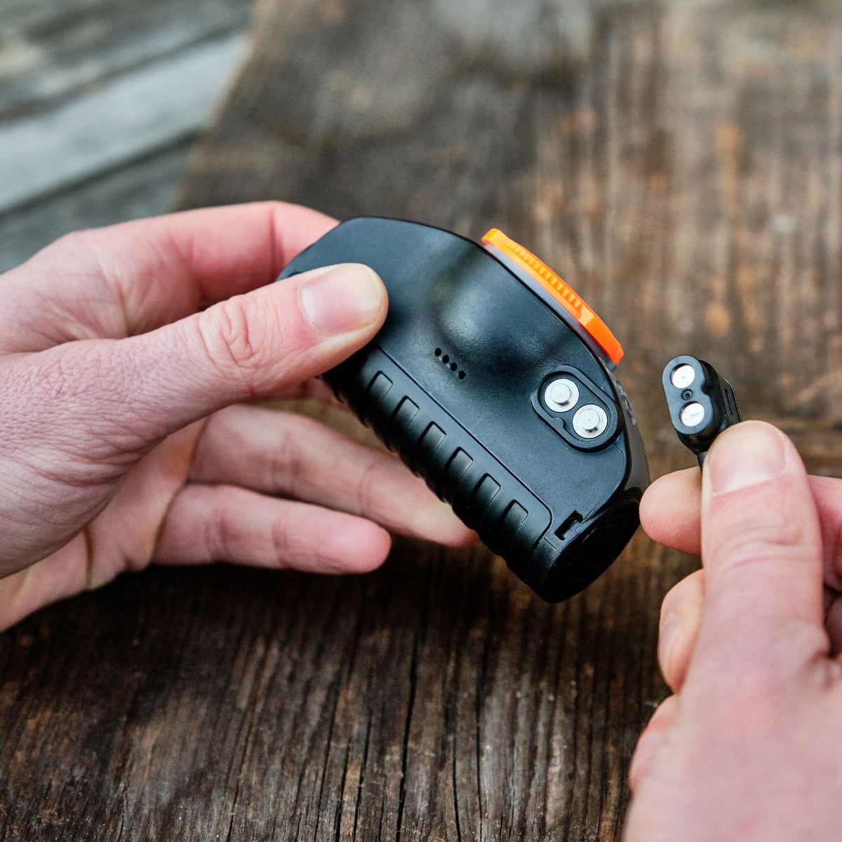 Hands clipping the magnetic charging connector onto a Ledlenser MH lamp head