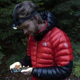 Walker in a red down jacket using the Ledlenser app on a phone while wearing the MH11