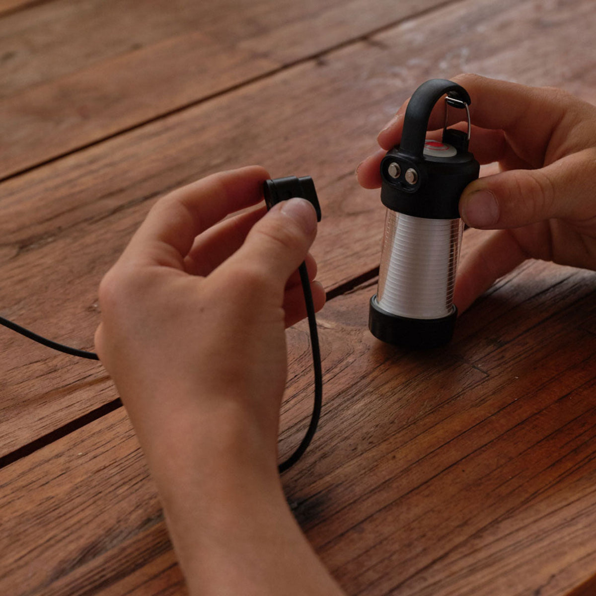 Hands connecting the magnetic charging cable to the Ledlenser ML4