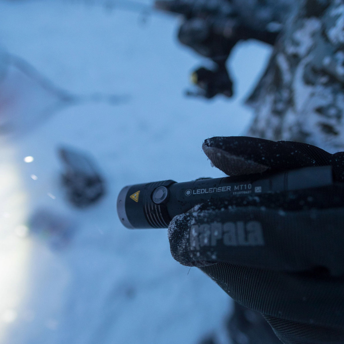 Gloved hand holding the Ledlenser MT10 torch in the snow