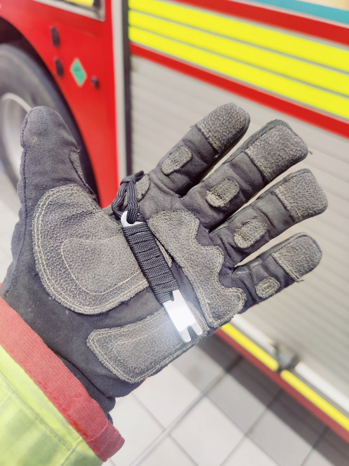 Black Mini Pry Bar lying across a firefighter's gloved palm