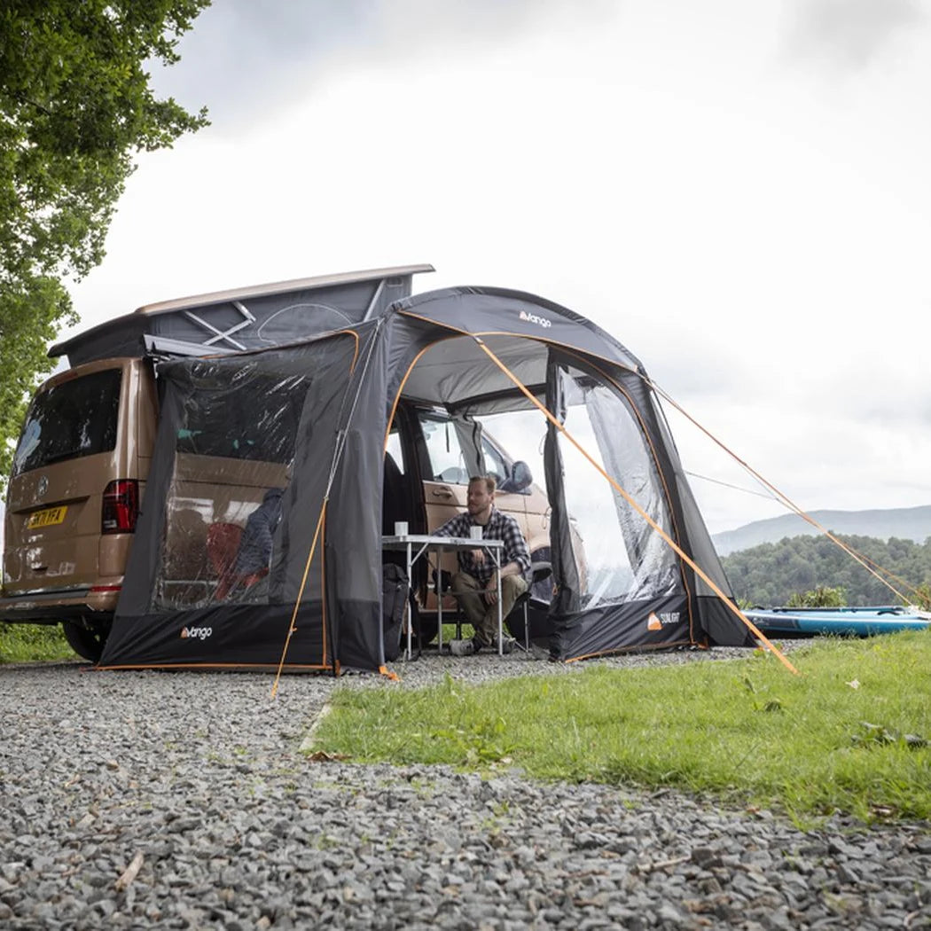 Campers sitting inside the Vango Sunlight awning beside their campervan