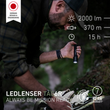 Man using the Ledlenser TAC6R torch to search a bag in woodland, with 2000 lumens, 370m and 15 hour figures