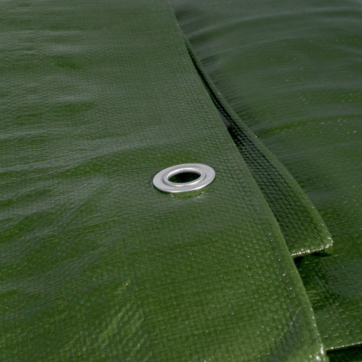 Close-up of an aluminium eyelet in the green side of the Green/Brown L-Grade Tarpaulin 3m x 3m