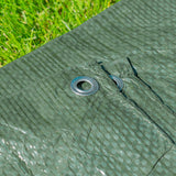 Close-up of an aluminium eyelet on the Green S-Grade Tarpaulin 1m x 1m lying on grass