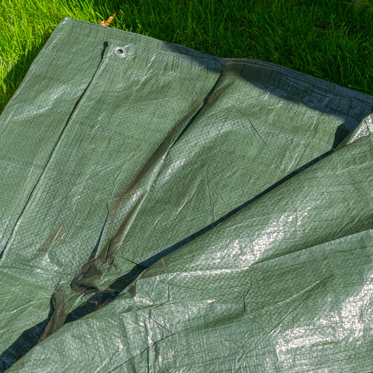 Green S-Grade Tarpaulin 1m x 1m spread on grass, showing the folded sheet and fabric sheen