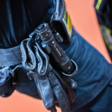 Ledlenser tactical torch carried bezel-down in a belt holster next to a pair of leather gloves