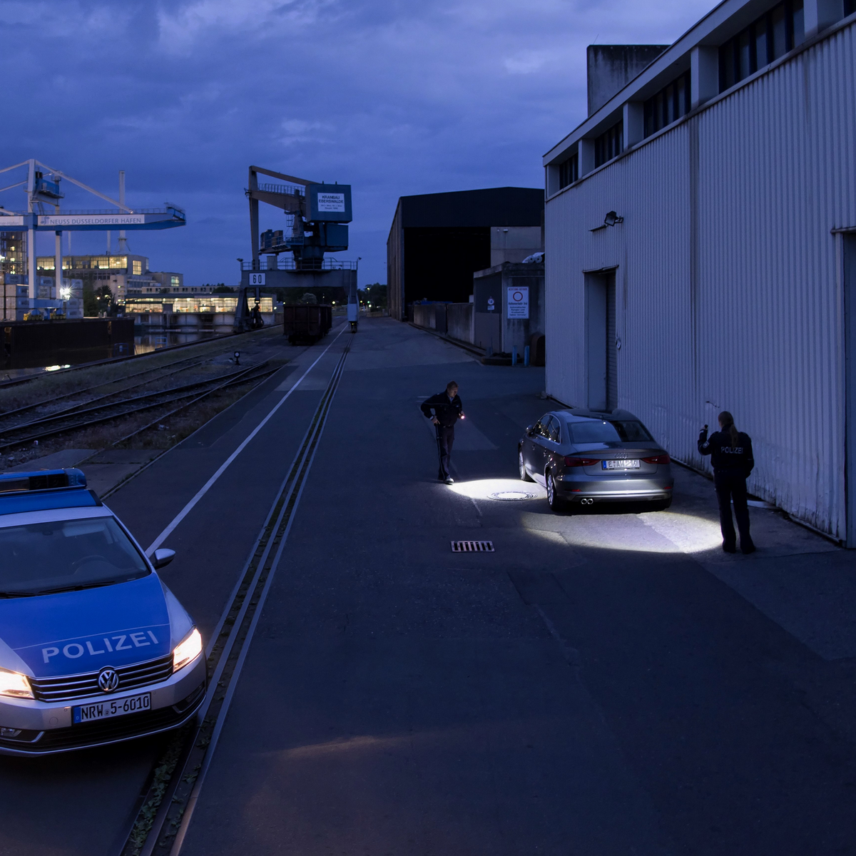 Police officers searching around a parked car at night with torches
