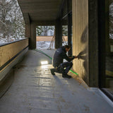 Tradesman sealing a timber wall on a covered balcony, lit by a Ledlenser floodlight standing on the floor