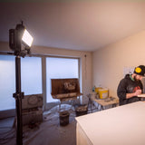 Ledlenser area light on a tall stand lighting a room under renovation while a plasterer works