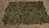 Overhead view of the Zero Alpha Designs hide sheet spread flat on gravel, garnish carried right out to the edges of the camouflage base